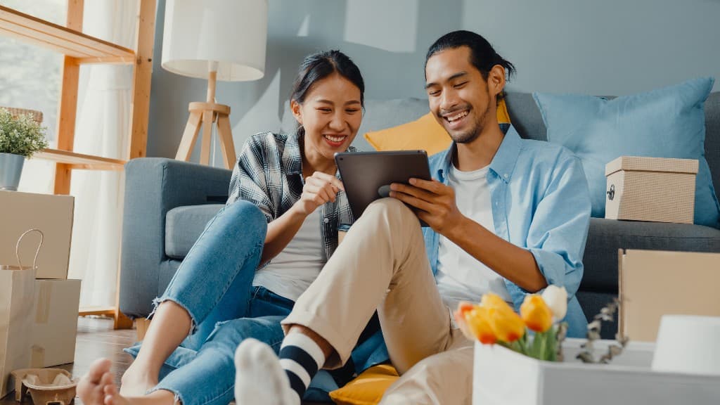 Young couple on the floor of their new home looking at a tablet together